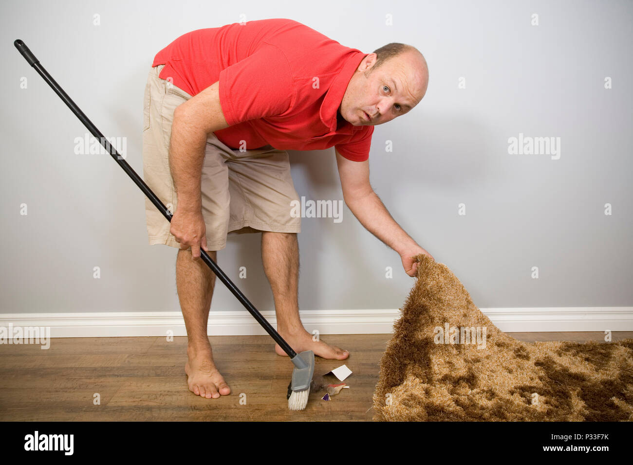 Ein Mann versteckt sich Müll unter den Teppich, Sprüche und Konzepte  Stockfotografie - Alamy