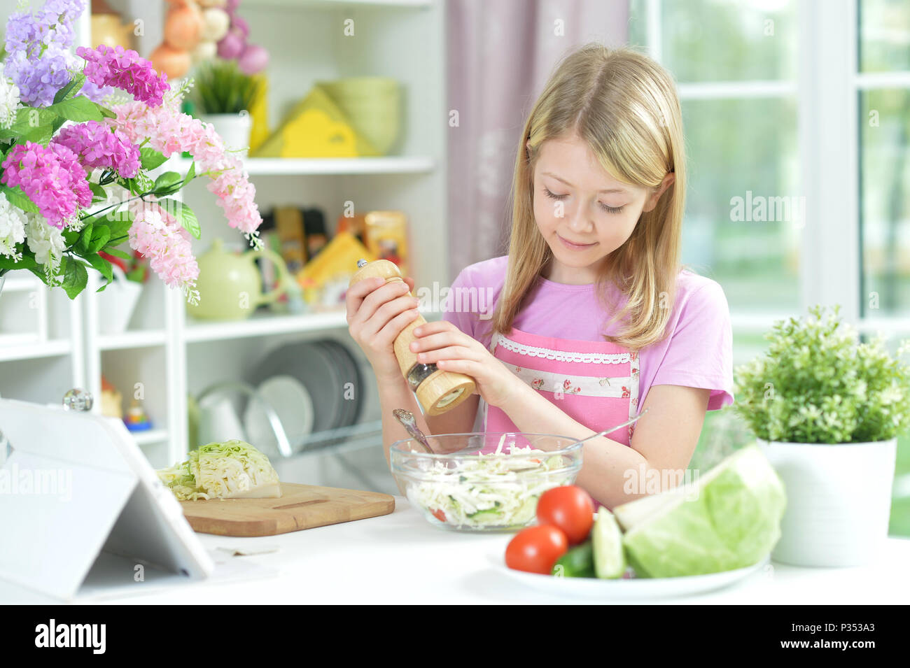 Süße kleine Mädchen würzenden frischer Salat Stockfoto