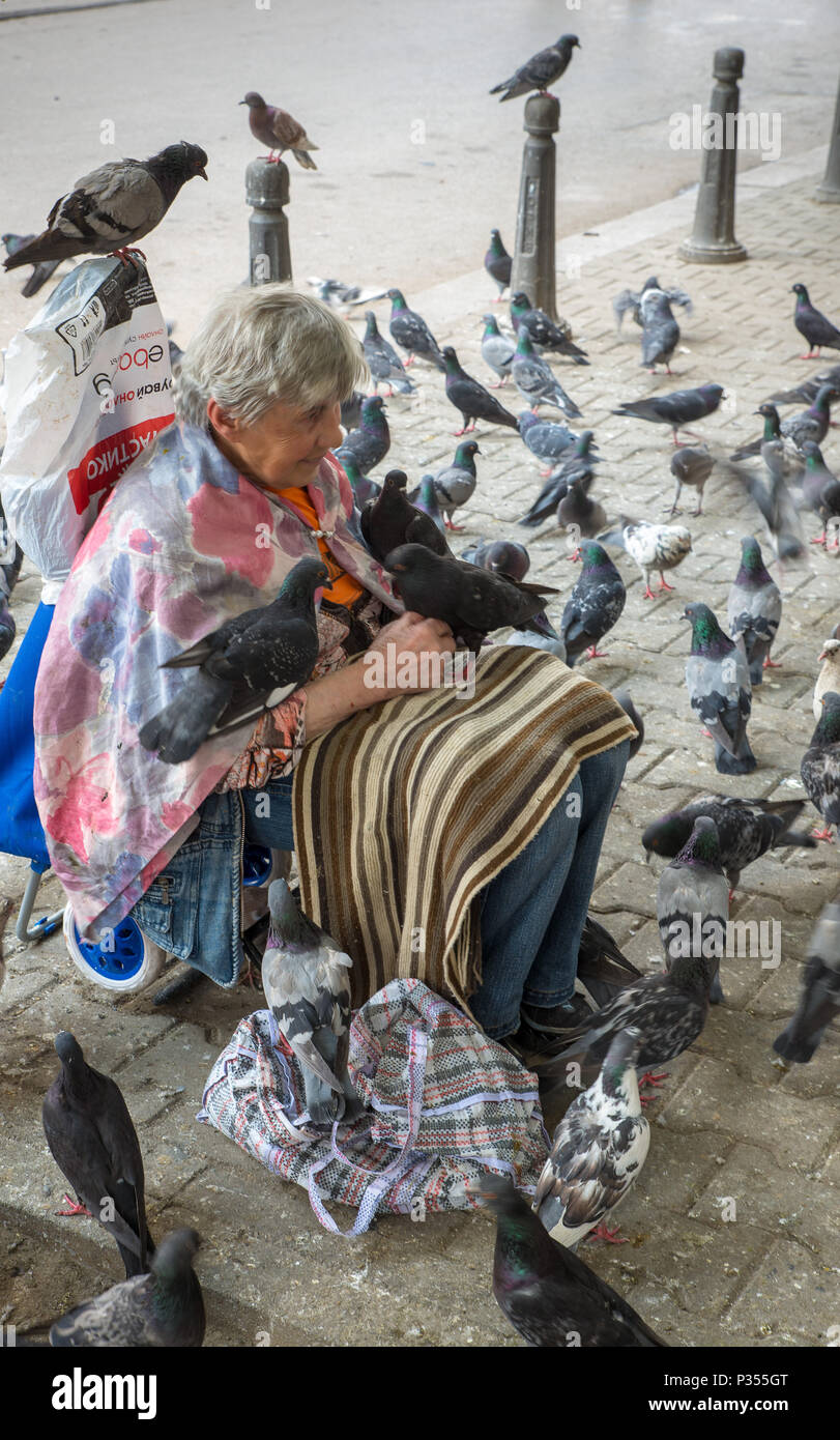 SOFIA, Bulgarien - Juni 7, 2018: eine obdachlose Bettler Frau wird von Tauben, während auf der Straße betteln in Sofia. Bulgarien Stockfoto
