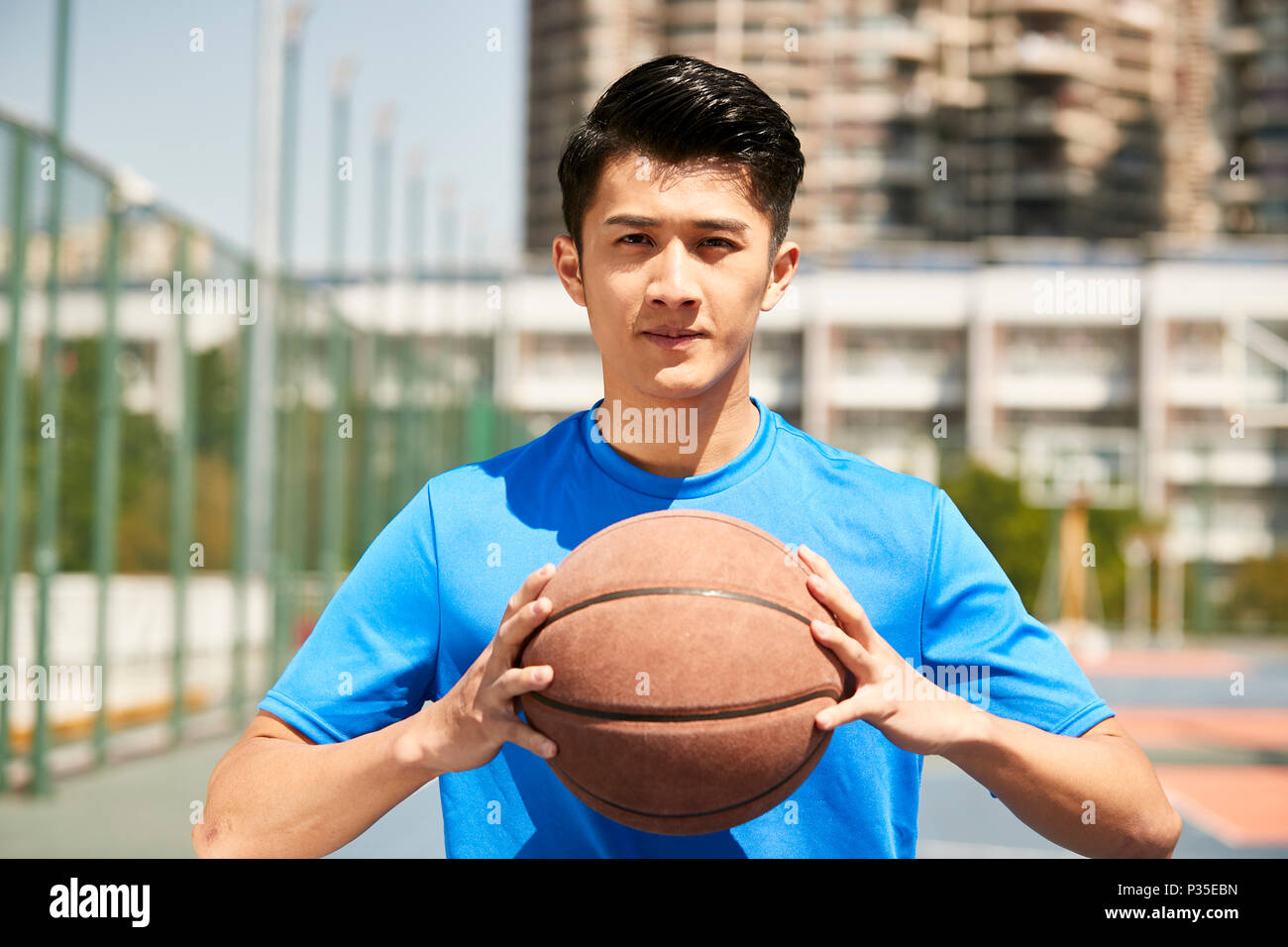 Jungen asiatischen männliche Spieler mit einem Basketball an der Kamera schaut. Stockfoto