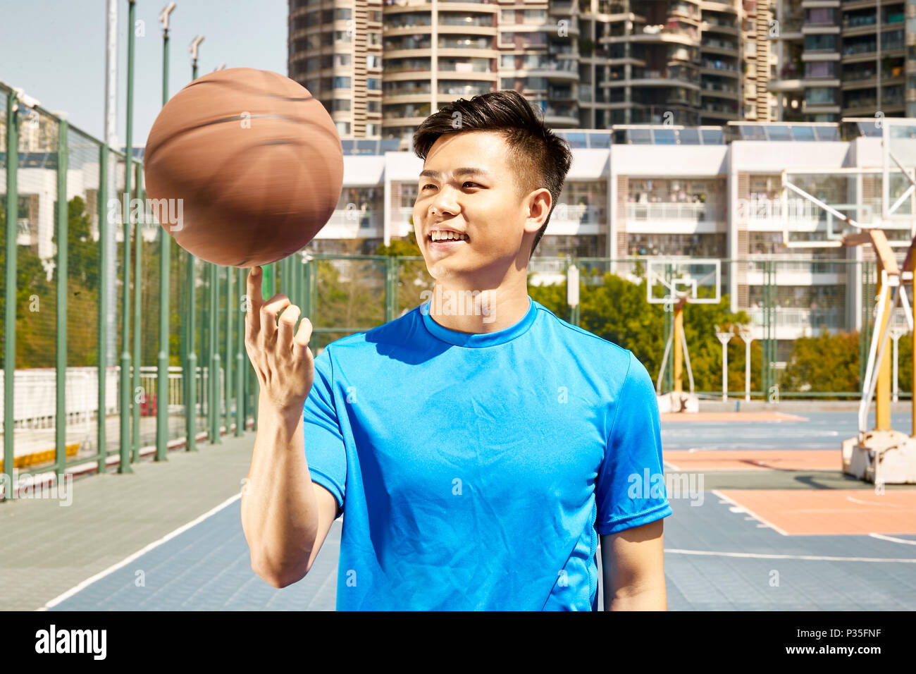 Glückliche junge asiatischer Mann spinnen ein Basketball am Finger. Stockfoto