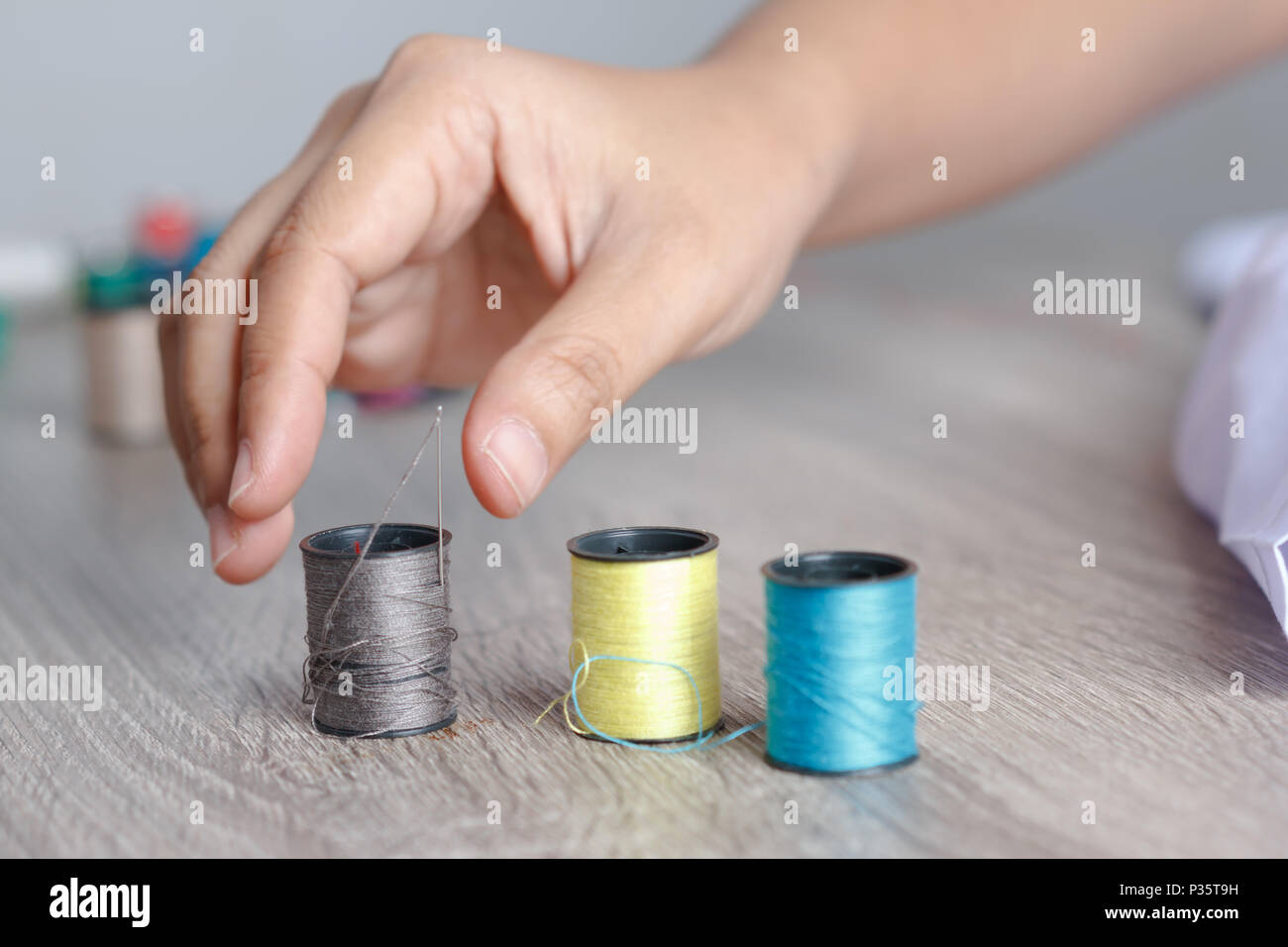 Die Hand der Frau wurde über bis zu dem Thread, auf den Tisch zu nähen platziert wurde. Stockfoto