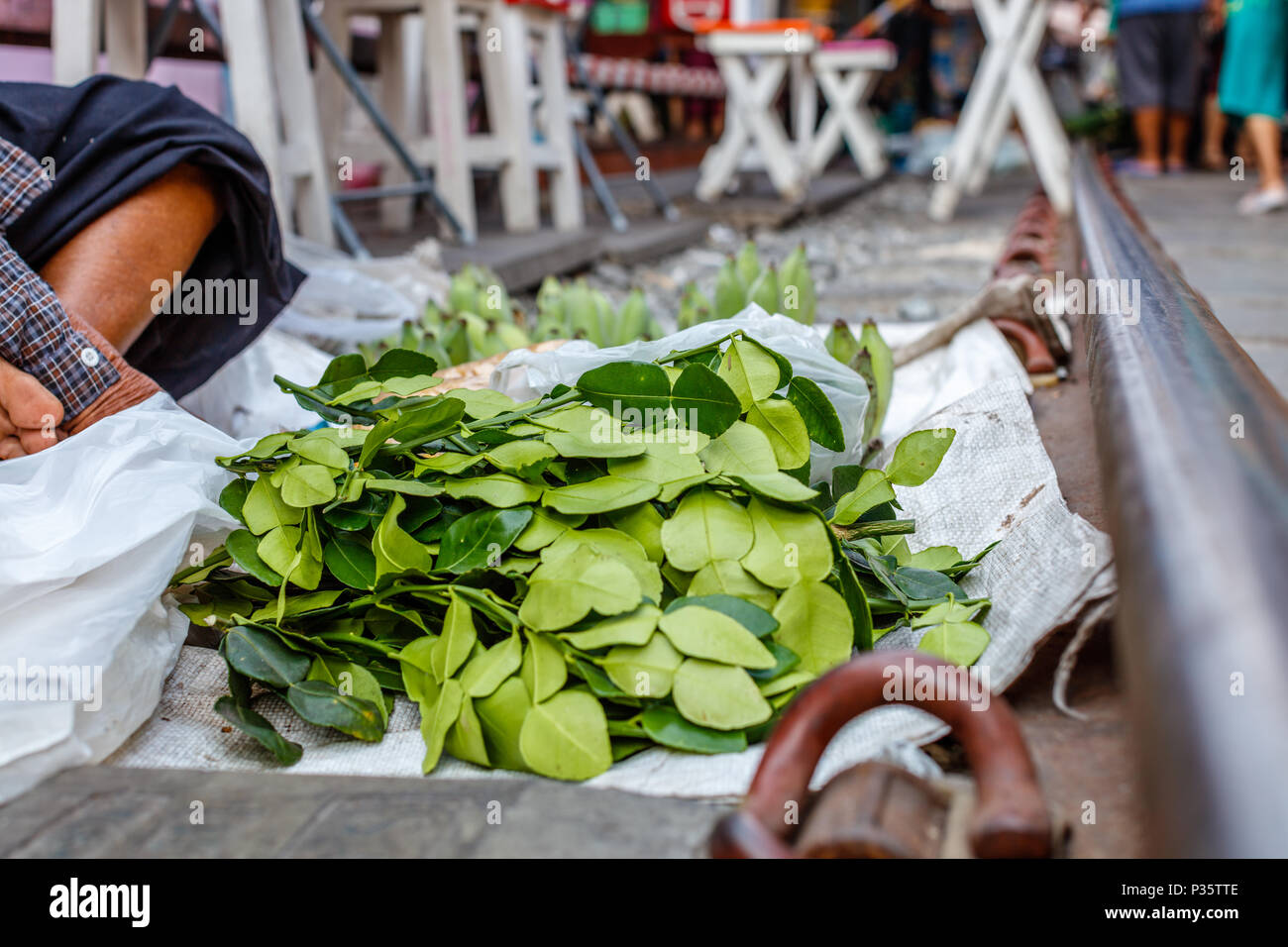 Straßenhändler verkaufen kaffernlimette Blätter zum Kochen am berühmten Maeklong Railway Markt. Samut Songkhram Thailand Stockfoto