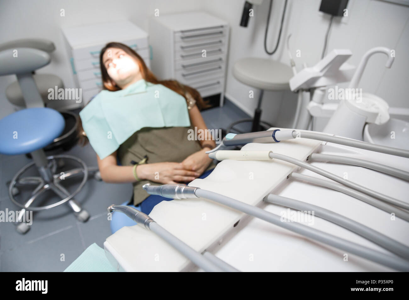 Junge weibliche im Behandlungsstuhl sitzen in Klinik Zimmer mit Anlagen in Soft Focus. Stockfoto