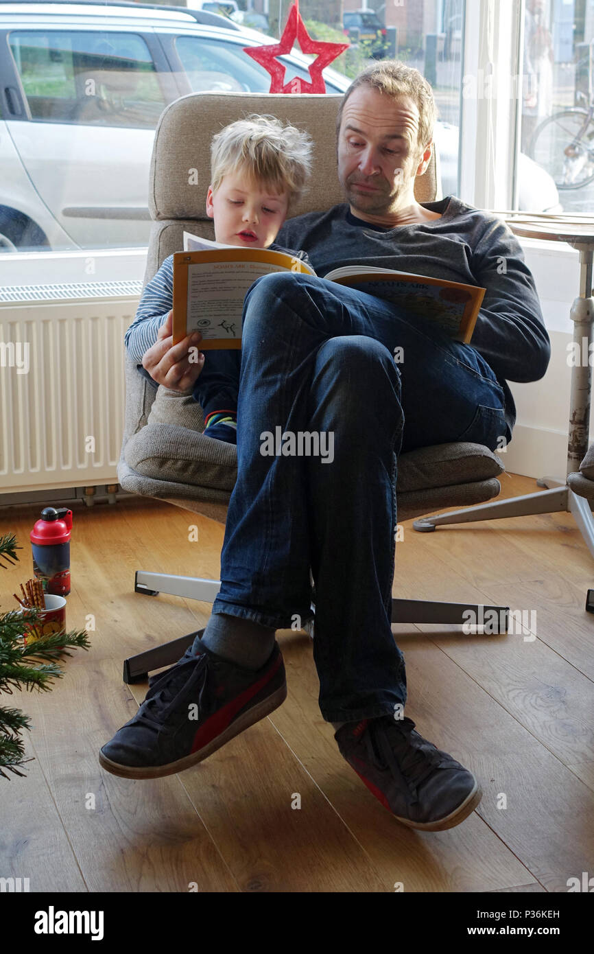 Utrecht, Niederlande, Vater betrachtet ein Bilderbuch mit seinem Sohn Stockfoto