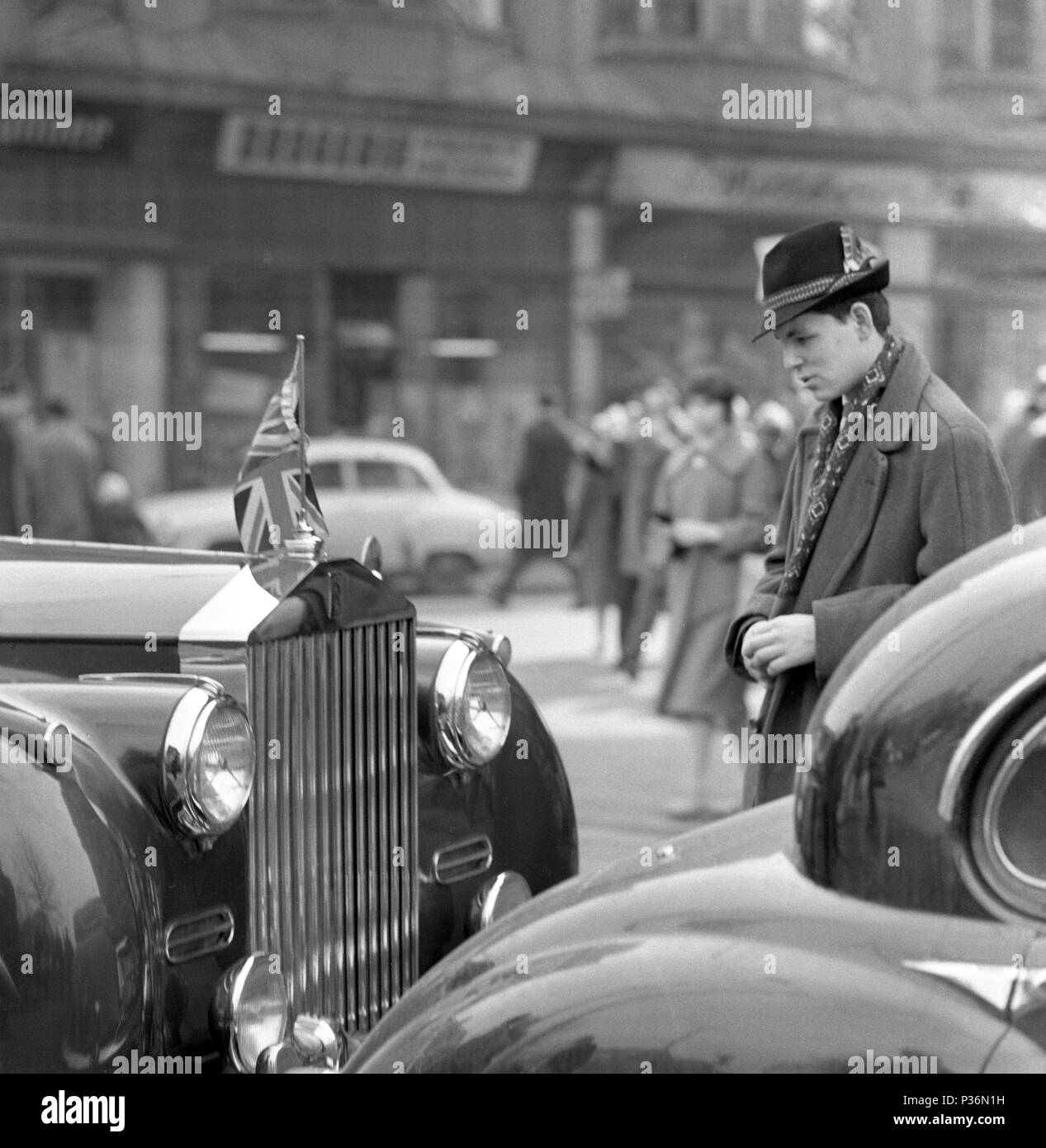 Berlin, DDR, junger Mann in Hut sucht in Erstaunen an einem Auto mit der nationalen Flagge von Großbritannien auf der Kuehler Stockfoto