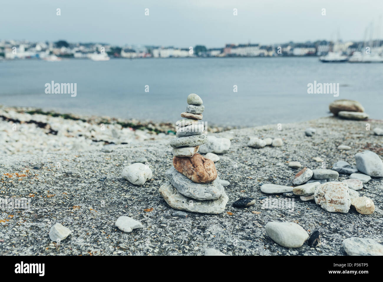Die Steine der Pyramide auf Kiesel-strand symbolisiert Stabilität, Zen, Harmonie, Balance. Flache Tiefenschärfe mit der Stadt im Hintergrund Stockfoto