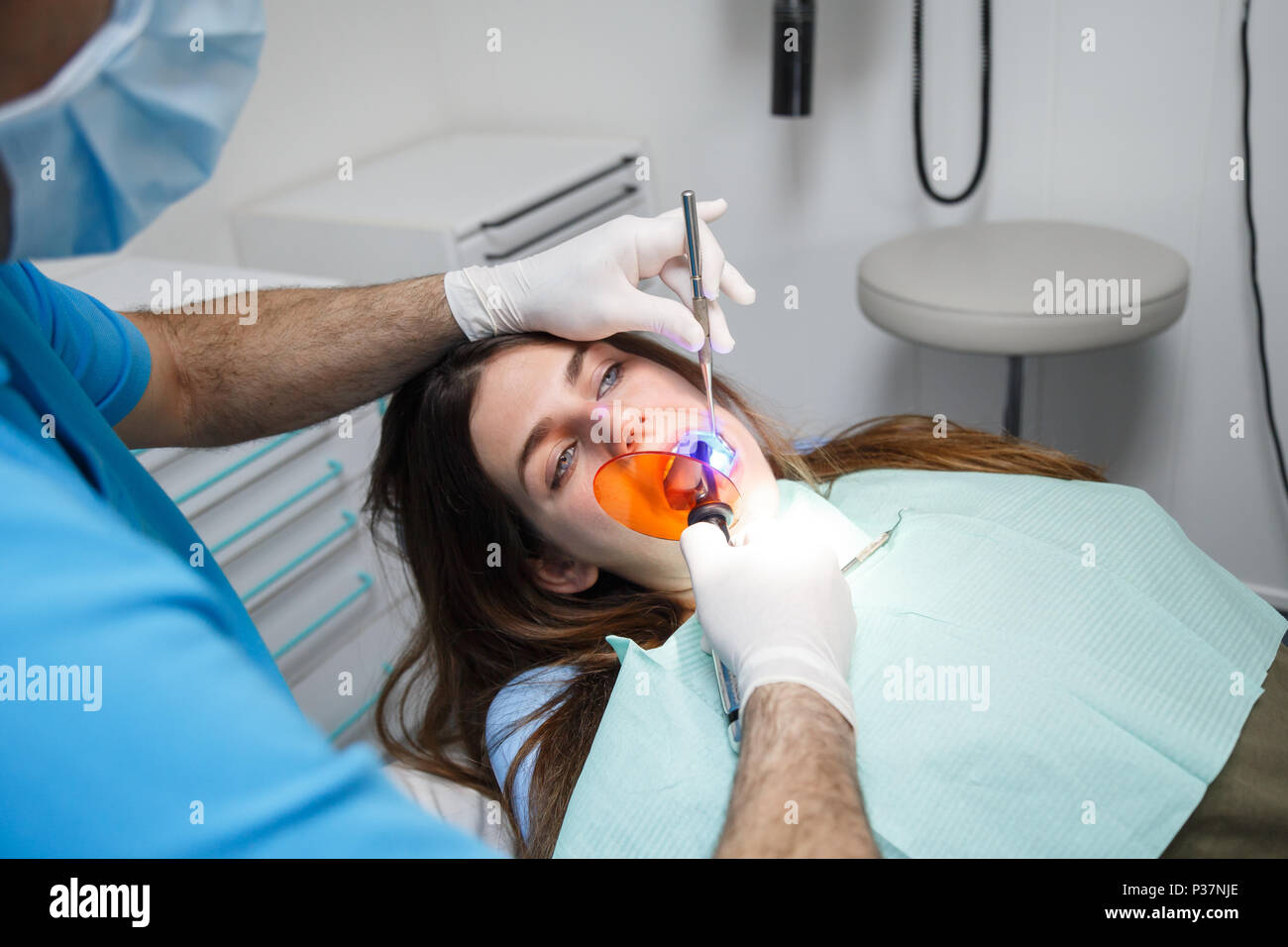 Erntegut Blick auf die Hände der Zahnarzt in Handschuhe, Befüllung von Zahn zu jungen Frauen. Stockfoto