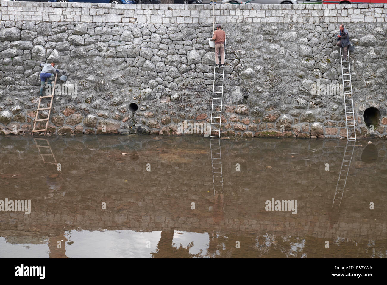 Arbeitnehmer die Aufrechterhaltung der steinernen Bank der Miljacka River in der Innenstadt von Sarajevo, Bosnien und Herzegowina, Europa. Stockfoto