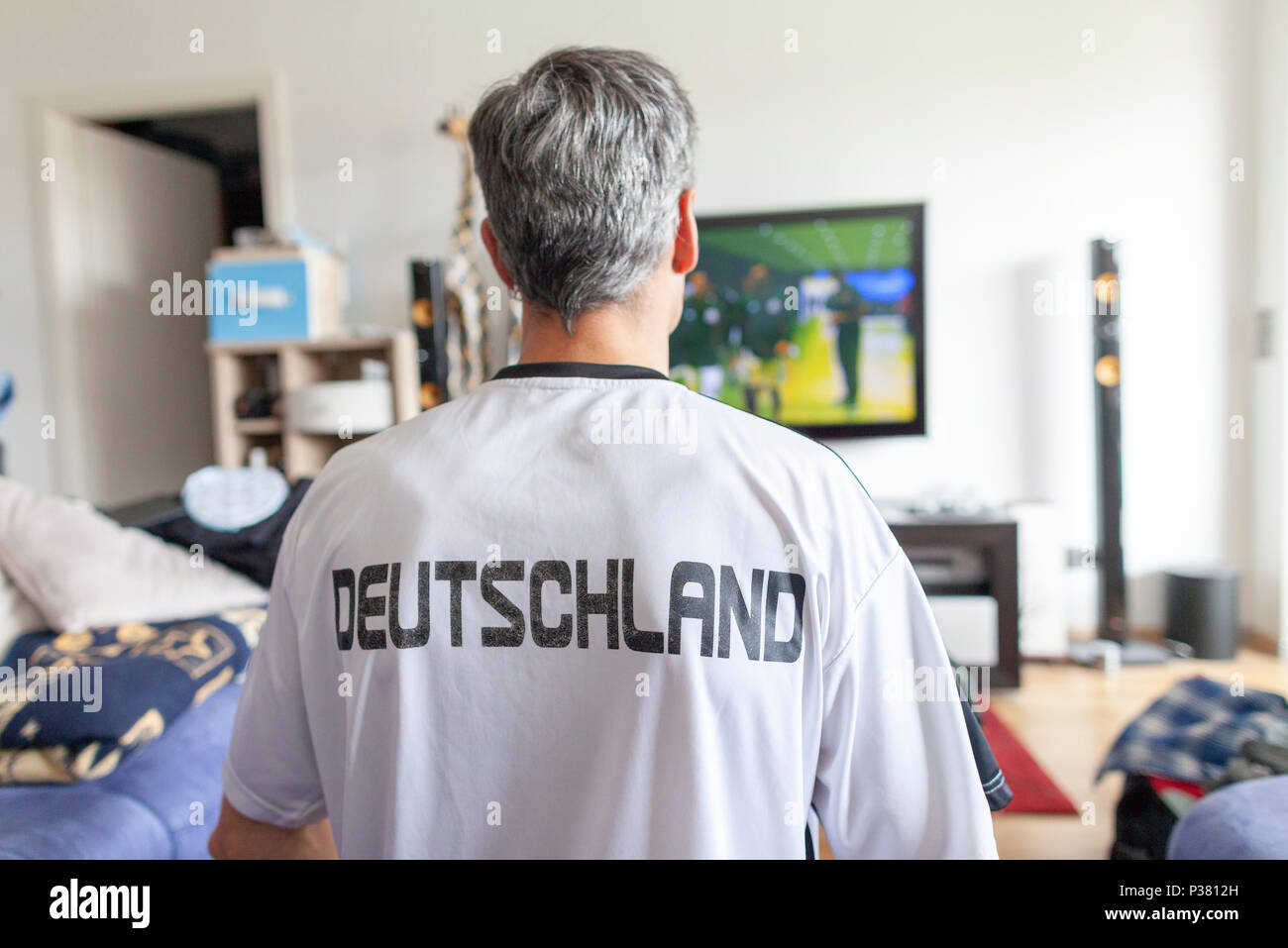Deutscher fan sitzt in einem Deutschland (Deutschland) Jersey vor einem Fernseher Stockfoto