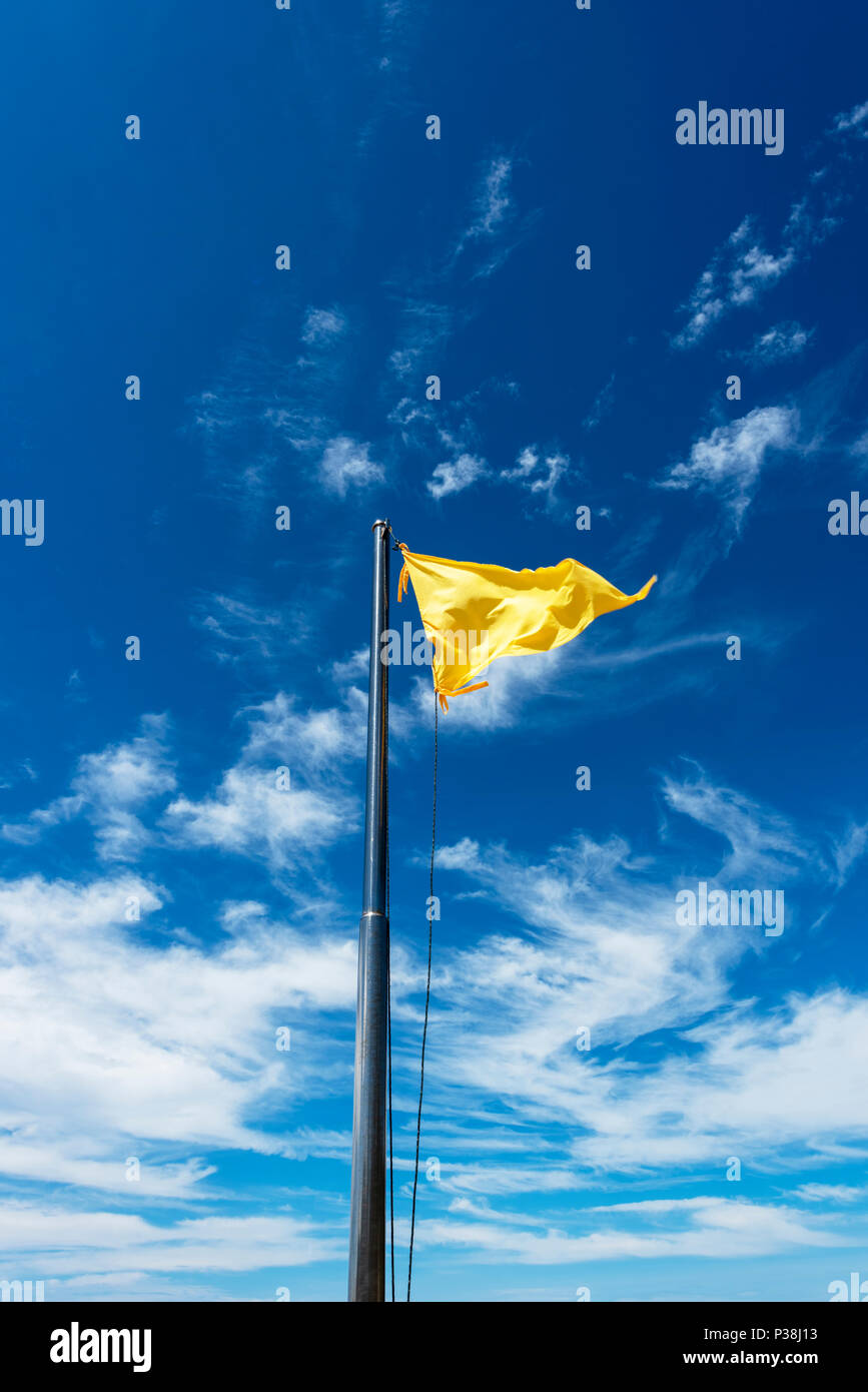 Gelbe Flagge auf einer Stange flattern im Wind gegen einen strahlend blauen Himmel in Kota Kinabalu, Borneo Stockfoto