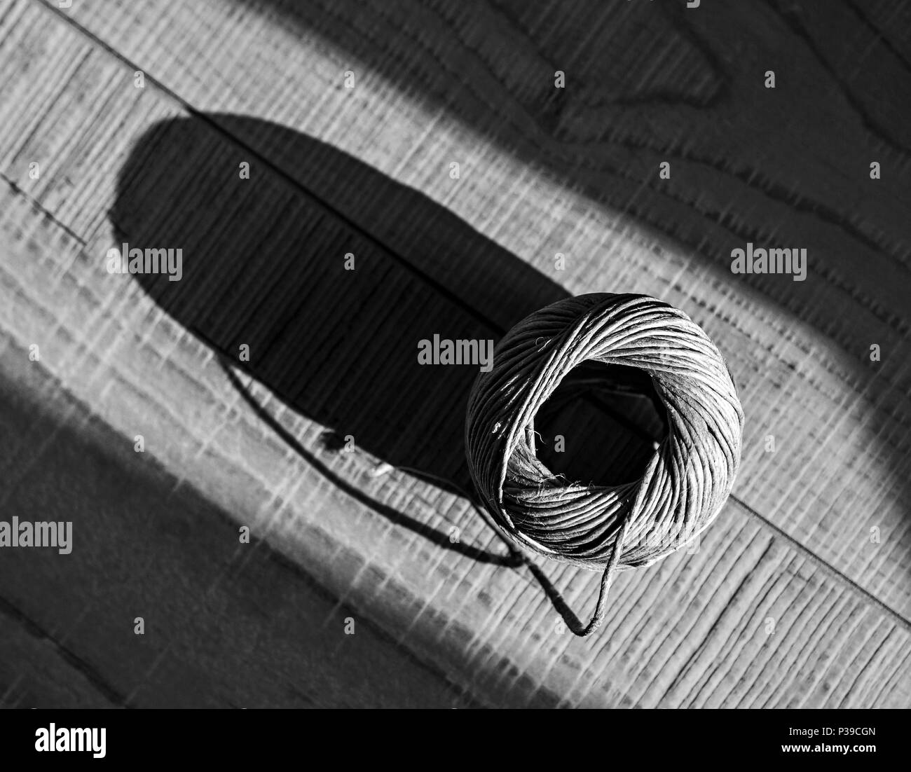 Stillleben mit braunen Seil Ball auf dem hölzernen Hintergrund. Top View, Schwarze und weisse Diagonale Komposition Stockfoto