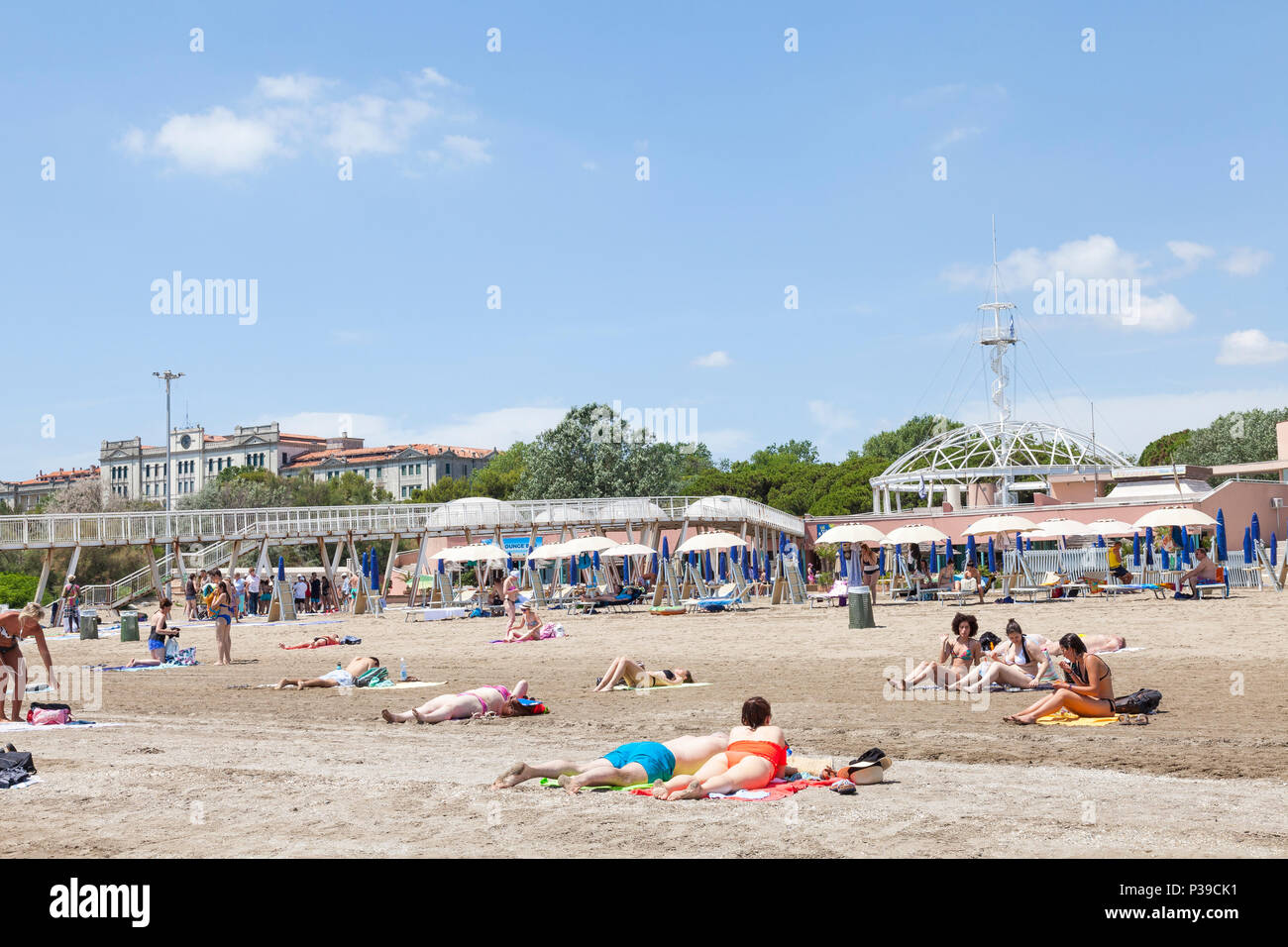 Menschen beim Sonnenbaden auf Blue Moon Beach, Lido di Venezia, die Insel Lido, Venedig, Venetien, Italien, auf einer sonnigen späten Frühling. Pier, Restaurants, Beobachtung Stockfoto