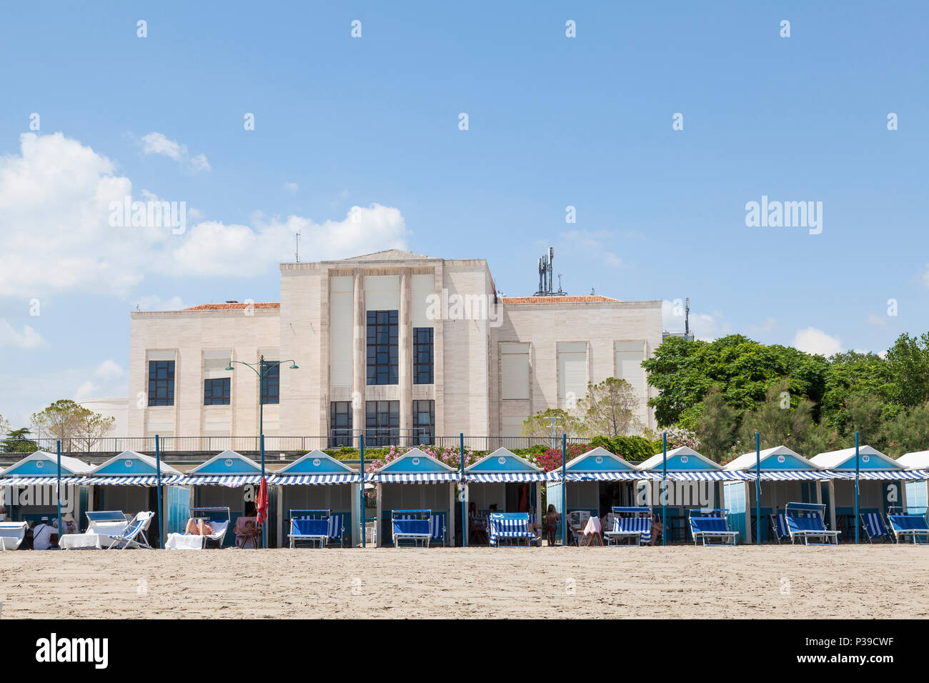 Blau Cabanas am Strand oder Muttern an einem Sandstrand am Lido di Venezia, Venedig, Venetien, Italien Vor dem Lido Casino. Menschen sonnenbaden, auf recliner Cha Stockfoto