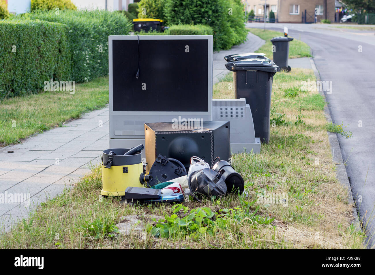 Elektronische Abfall mit einem Fernseher, Staubsauger und andere elektrische Geräte, die am Straßenrand Stockfoto