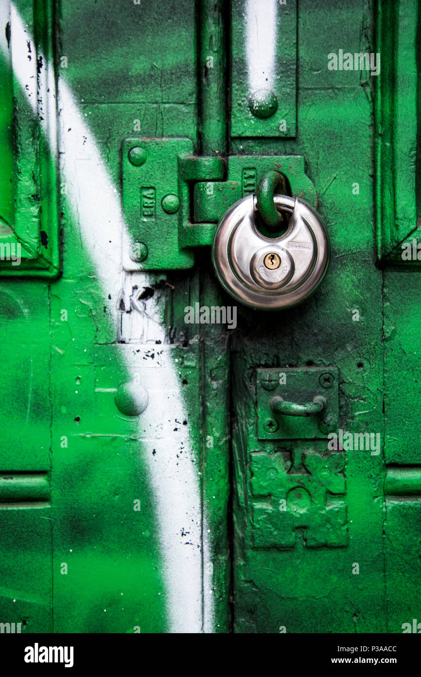 Eine Runde silber Vorhängeschloss ein Grün und Weiß graffiti Tür Stockfoto