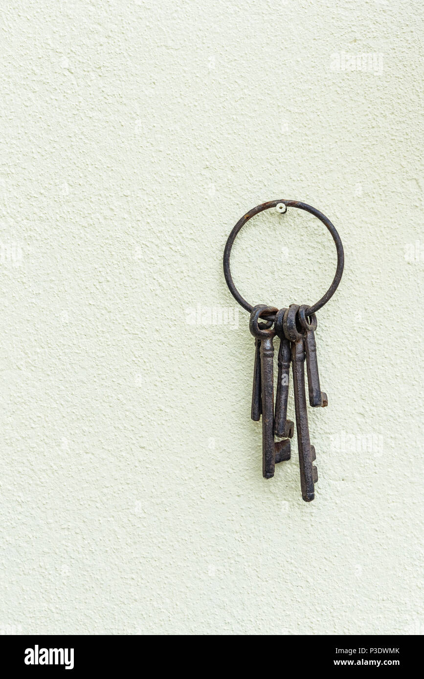 Rostige alte Schlüssel hängen an einer Creme texturierte Wand. Korrodierte Schlüsselanhänger aus Metall und Tasten. Stockfoto