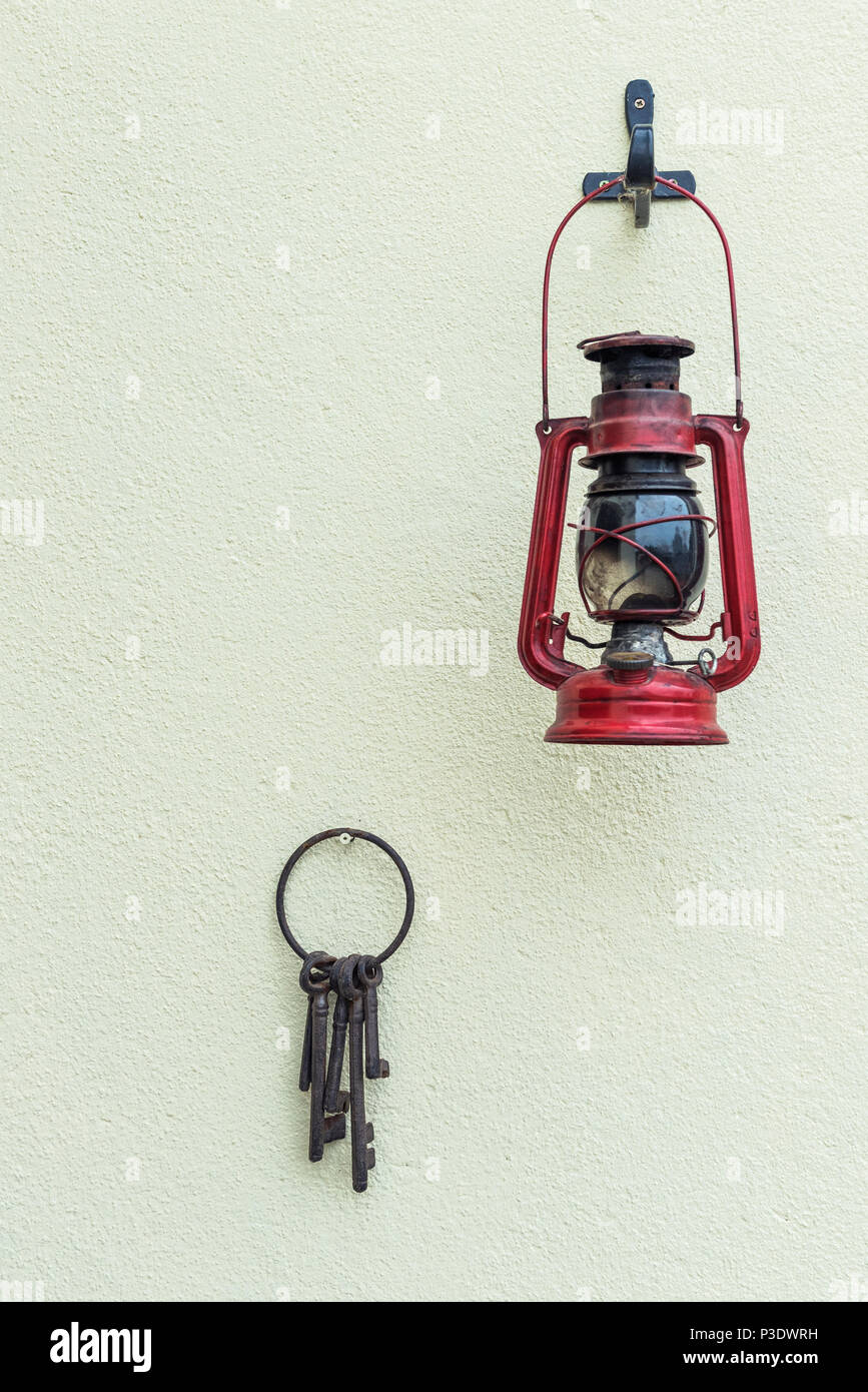 Alte Hurrikan Lampe und Tasten hängen an einer strukturierten Wand. Stockfoto