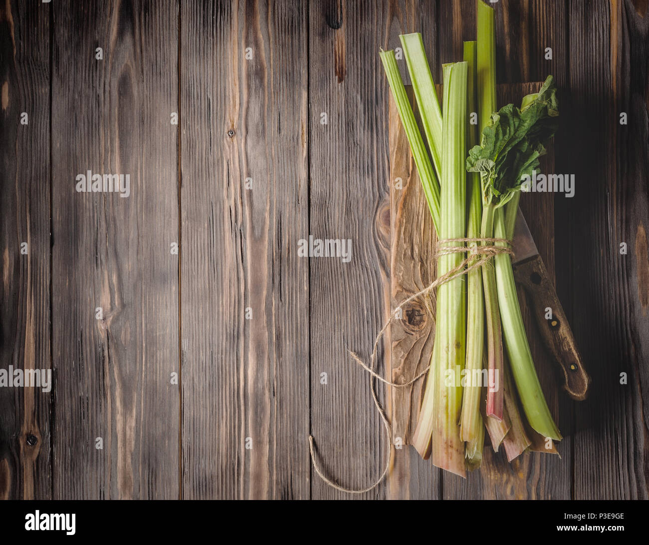 Stämme der frische junge Rhabarber mit Küchenmesser auf Schneidebrett Zutaten für Lebensmittel Rezepte gesunde Ernährung detox Bio Lebensmittel Gemüse auf Holz- Bac Stockfoto