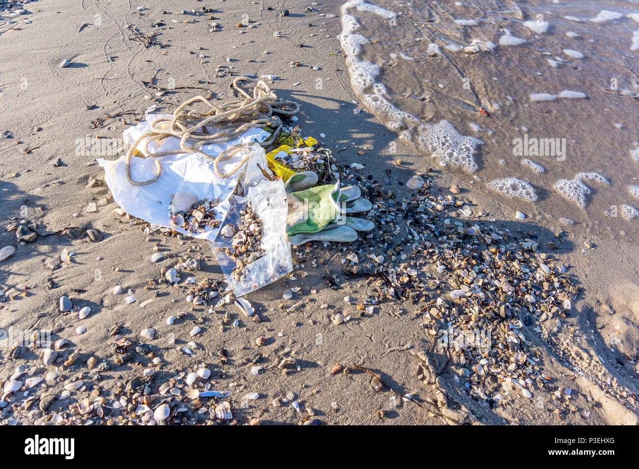 Eine Plastikflasche und anderen Müll auf dem Sand in der Nähe des Meeres, eine Nahaufnahme von einer verschmutzten Strand, Vejle, Dänemark, 6. Juni 2018 Stockfoto