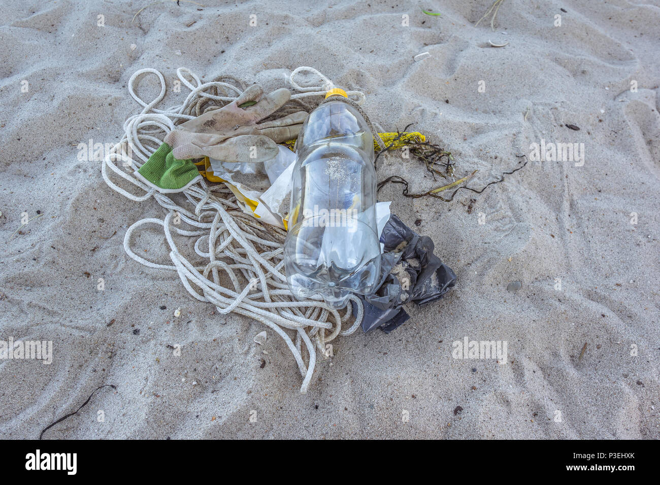 Eine Plastikflasche und anderen Abfall auf den Sand, eine Nahaufnahme von einer verschmutzten Strand, Vejle, Dänemark, 6. Juni 2018 Stockfoto