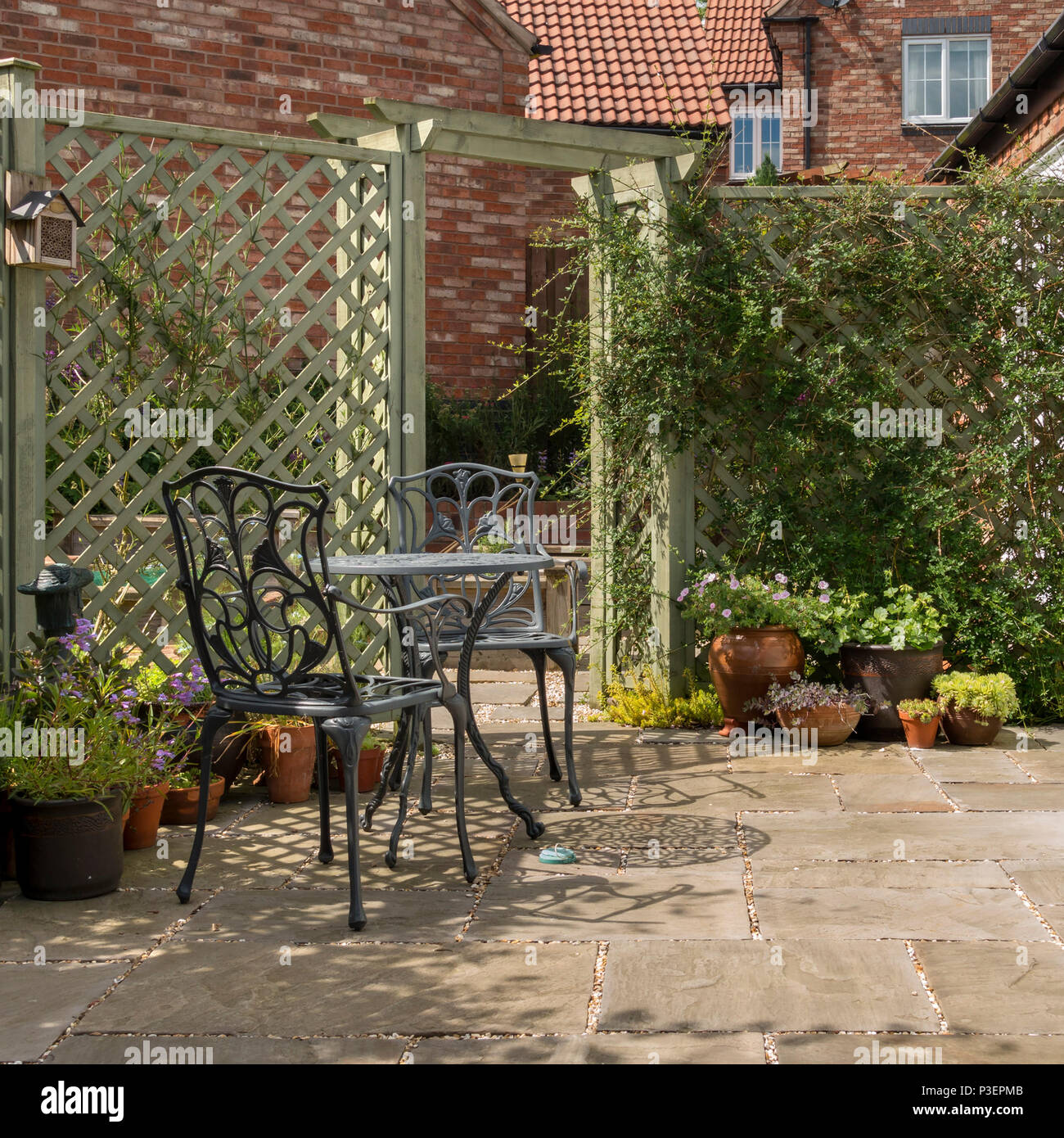 Kleine inländische Garten Terrasse mit Tisch und Stühlen, Natursteinplatten und lackierte Gitter Stockfoto
