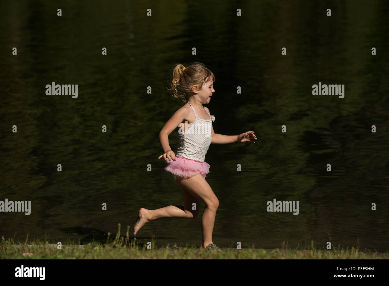 Süße Mädchen läuft in der Nähe der Flussufer Stockfoto