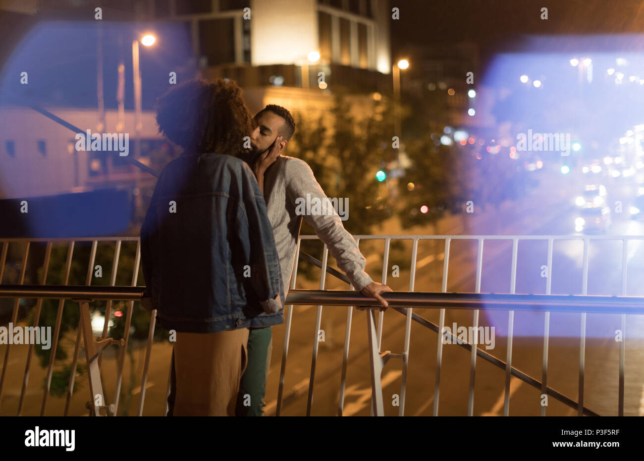 Paar einander küssen, während in der Nähe von Geländer stehend Stockfoto