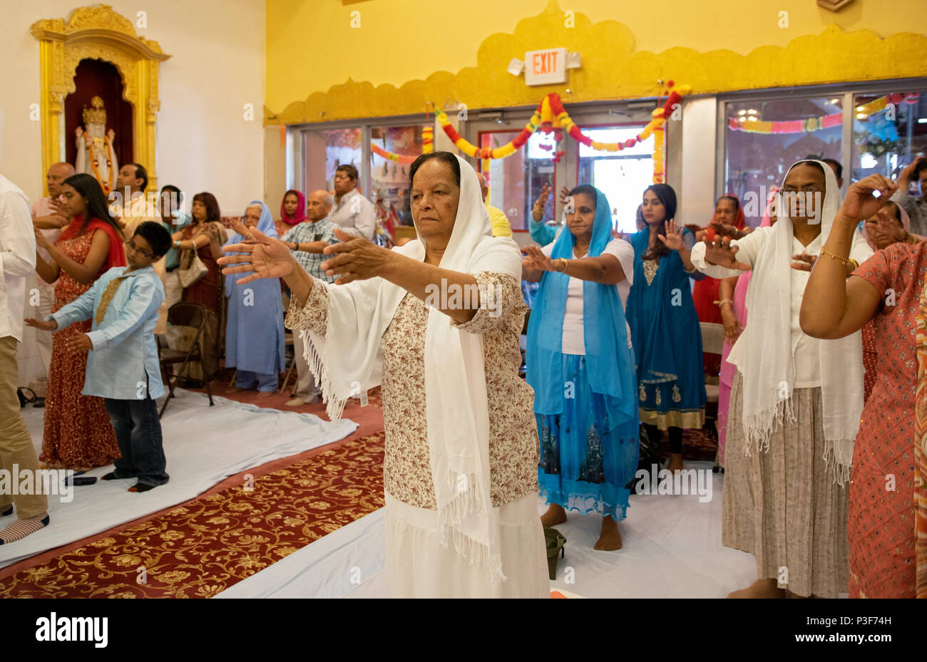 Frauen & Männer mit outreached Arme an den Shri Lakshmi Narayan Mandir Tempel in Richmond Hill, Queens, New York, zu beten. Stockfoto