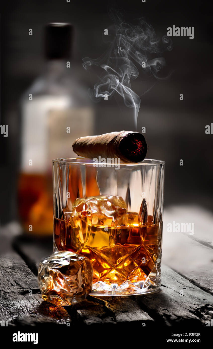 Zigarre und Glas mit Whiskey mit Eiswürfel Stockfotografie