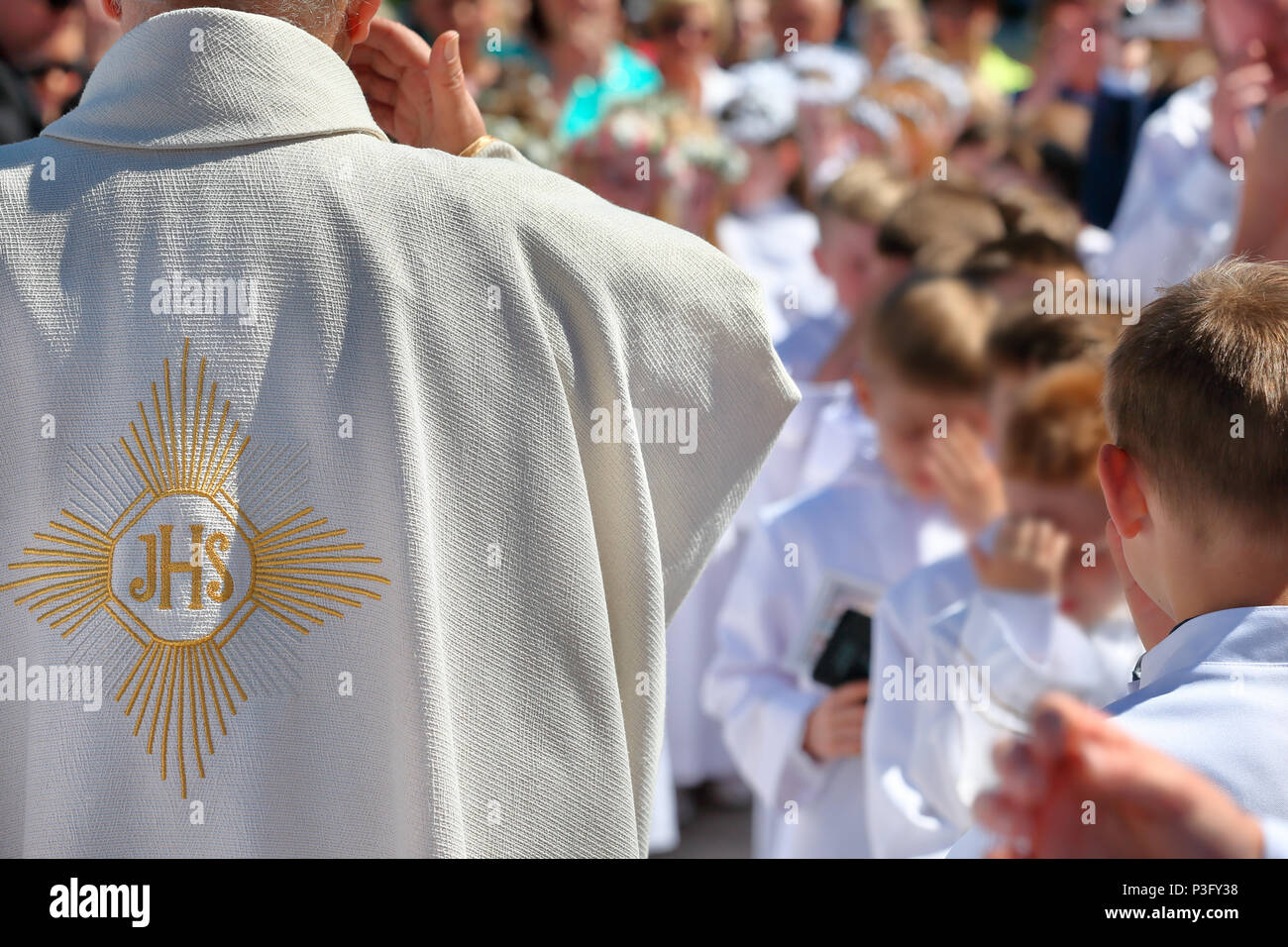 Priester mit Eltern und Kinder vor der Erstkommunion Stockfoto