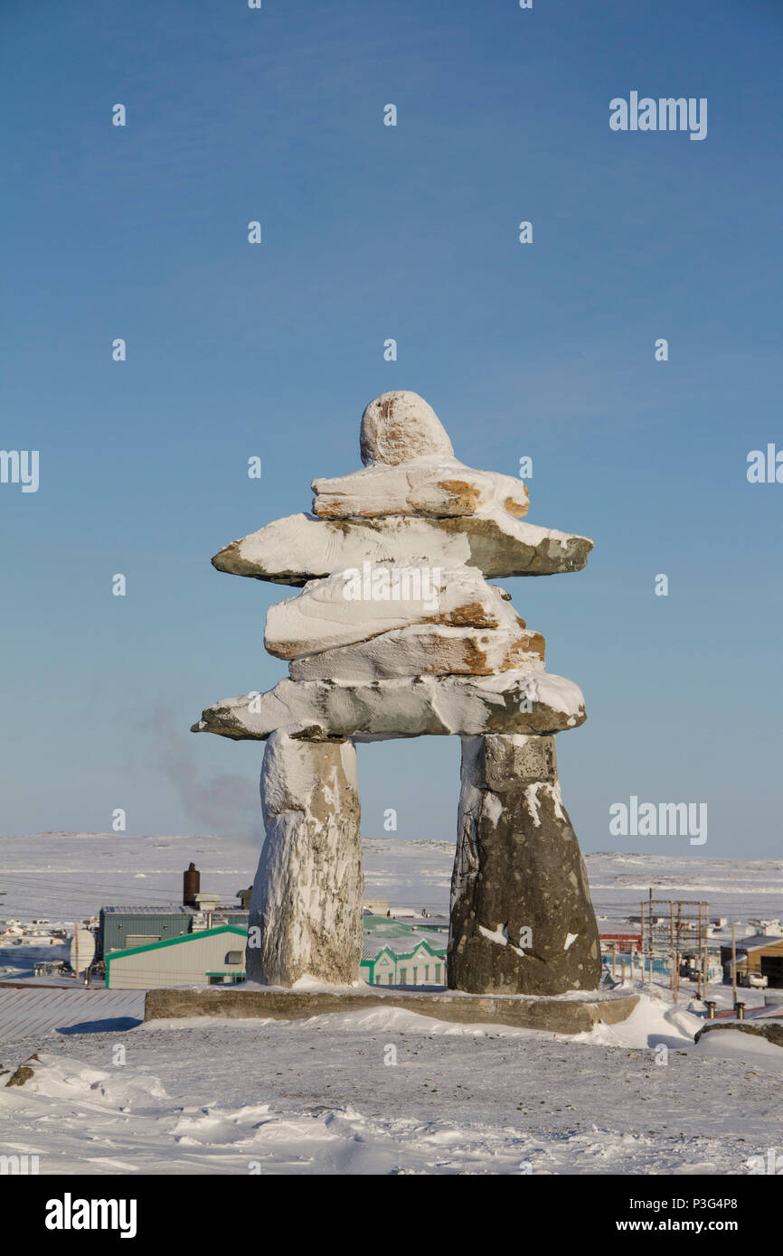 Inuksuk oder Inukshuk Wahrzeichen bedeckt mit Schnee auf einem Hügel in der Gemeinde Rankin Inlet, Nunavut, Kanada gefunden Stockfoto
