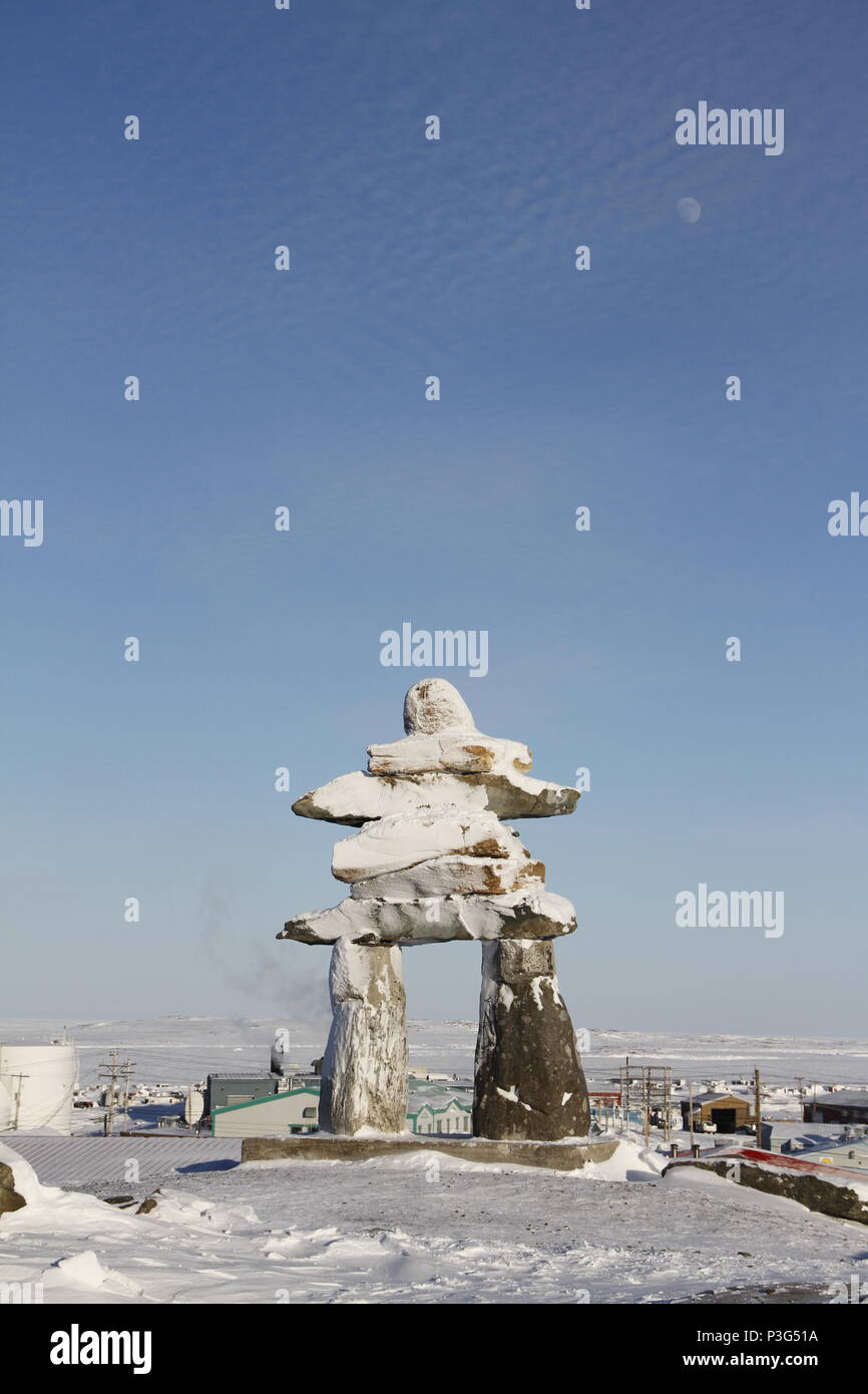 Inuksuk oder Inukshuk Wahrzeichen bedeckt mit Schnee auf einem Hügel in der Gemeinde Rankin Inlet, Nunavut, Kanada gefunden Stockfoto