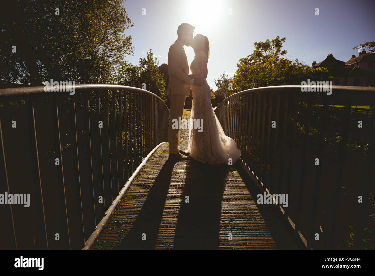 Braut und Bräutigam küssen Auf der Fußgängerbrücke im Garten Stockfoto
