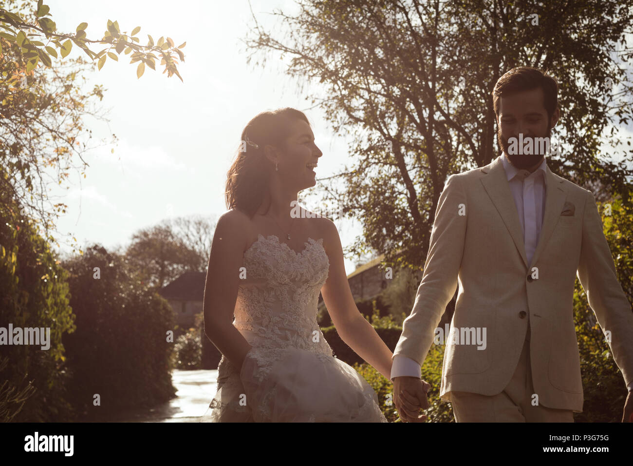 Braut und Bräutigam gehen Hand in Hand im Garten Stockfoto