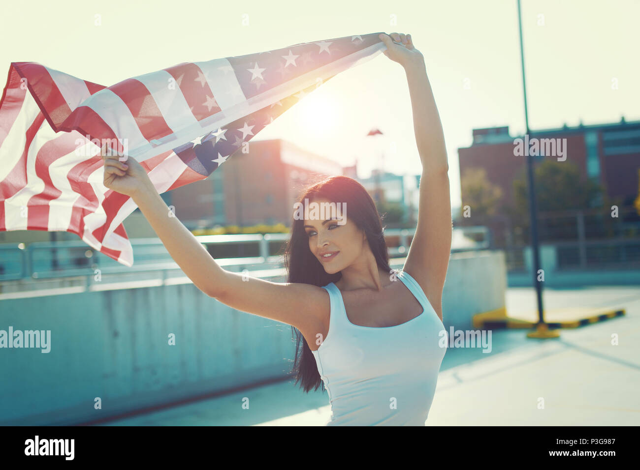 Junge Frau mit USA-Flagge über dem Kopf im Freien bei Sonnenuntergang Stockfoto