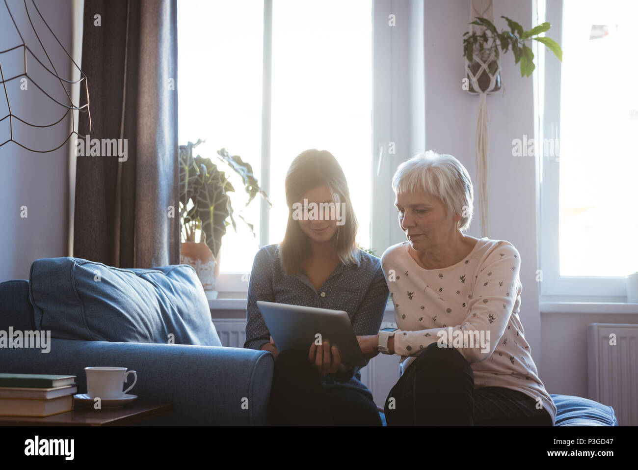 Ältere Frau und Tochter mit einem tab während des Standorts auf dem Sofa Stockfoto