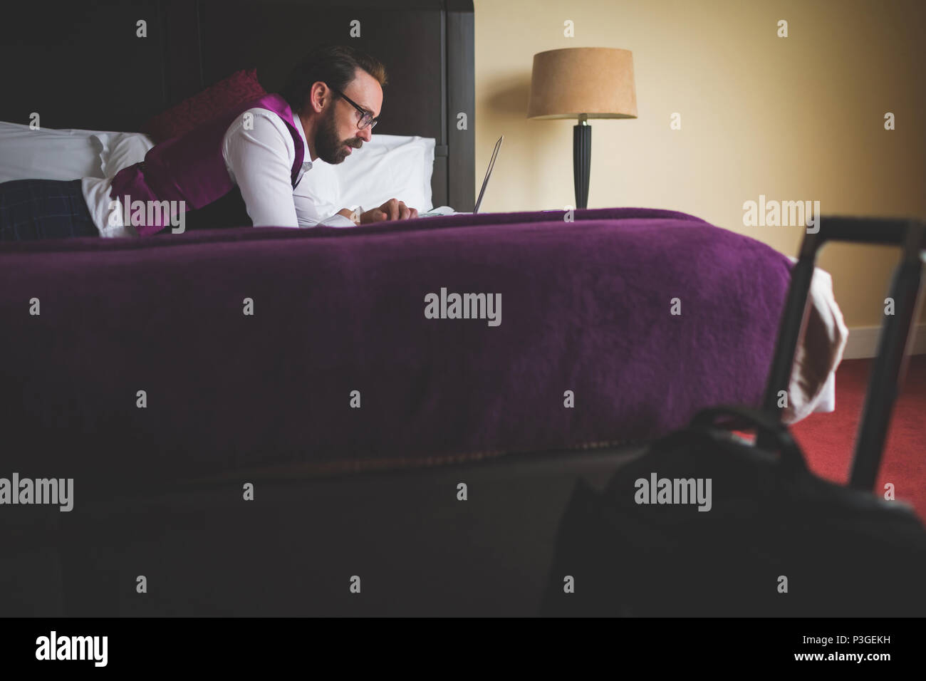 Geschäftsmann mit Laptop am Bett Stockfoto