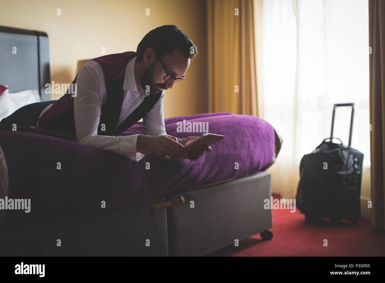 Geschäftsmann mit digitalen Tablet auf dem Bett Stockfoto