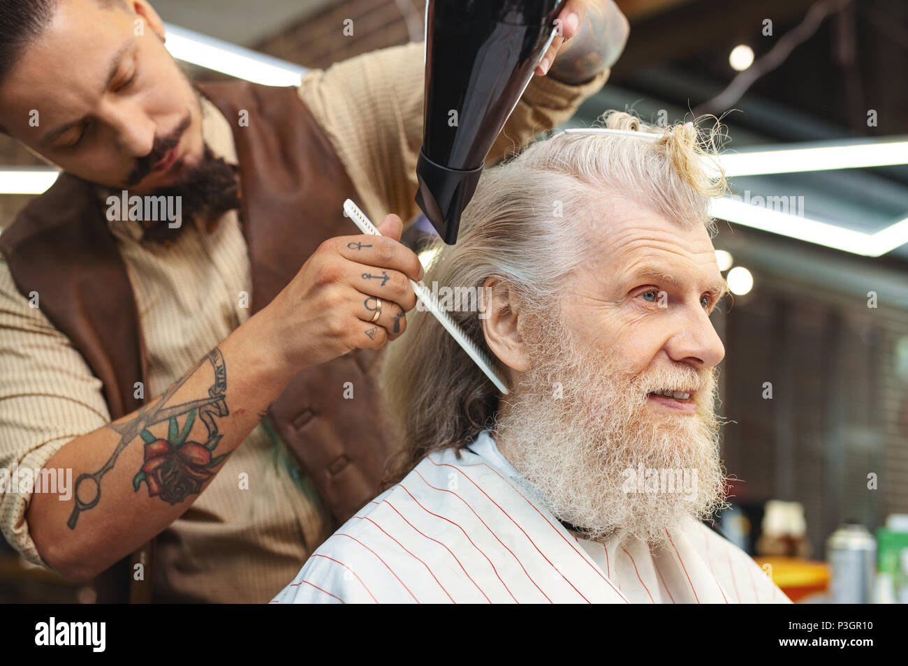 Nahaufnahme von tätowierten Arme, die mit Haartrockner Stockfoto