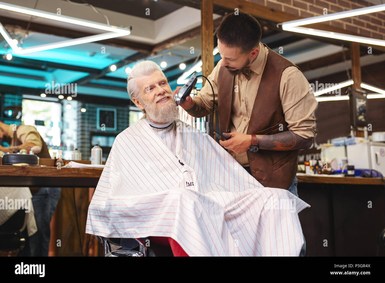 Freudige pensionierter Mann sitzt im barbershop Stockfoto