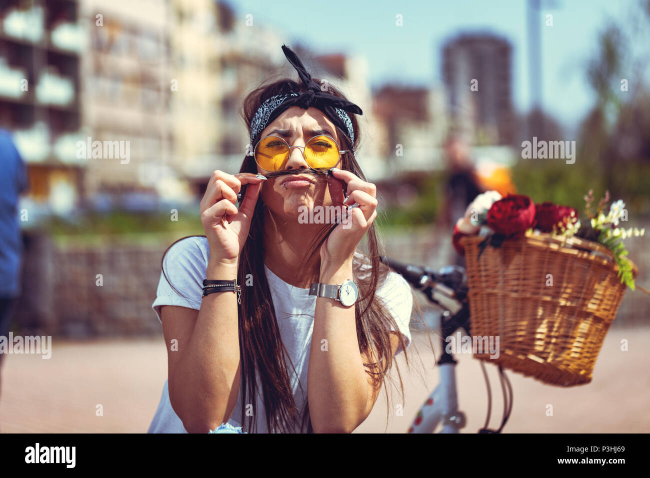 Recht glücklich junge Frau genießen und Spaß haben, schnurrbärte mit Haaren, in einem Sommer sonnigen Tag, neben dem Fahrrad mit Blumenkorb. Stockfoto
