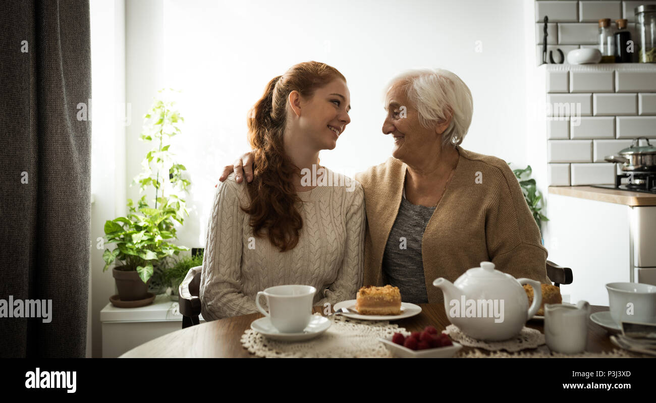 Großmutter und Enkelin an einander, während im Wohnzimmer sitzen Stockfoto
