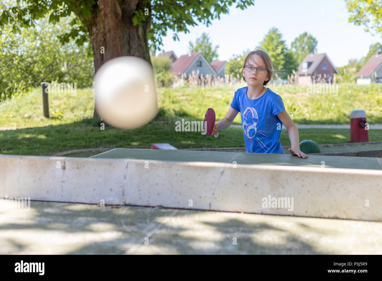 Ein 9 Jahre altes Mädchen spielt Tischtennis auf eine Tischtennisplatte. Sie spielt die einen Smash Stockfoto