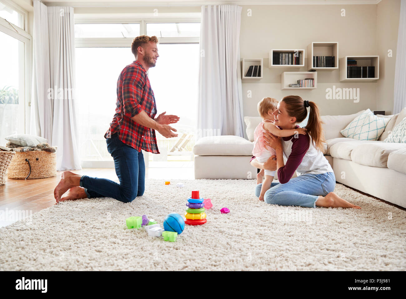 Kleinkind Mädchen zu Fuß von Dad im Wohnzimmer zu Mom Stockfoto