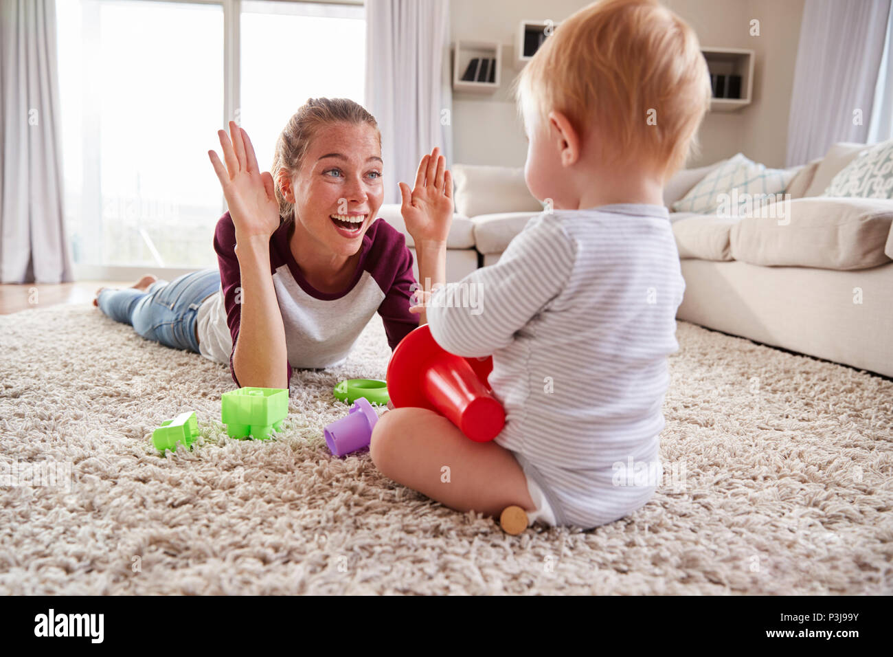 Junge Mutter liegen auf dem Boden spielen mit Kleinkind Sohn zu Hause Stockfoto