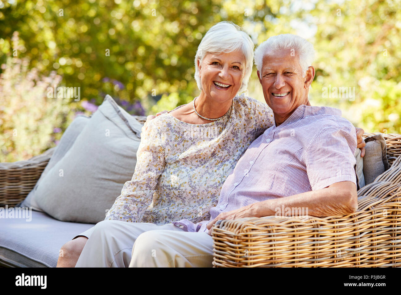 Gerne älteres Paar sitzt im Garten zu Kamera suchen Stockfoto