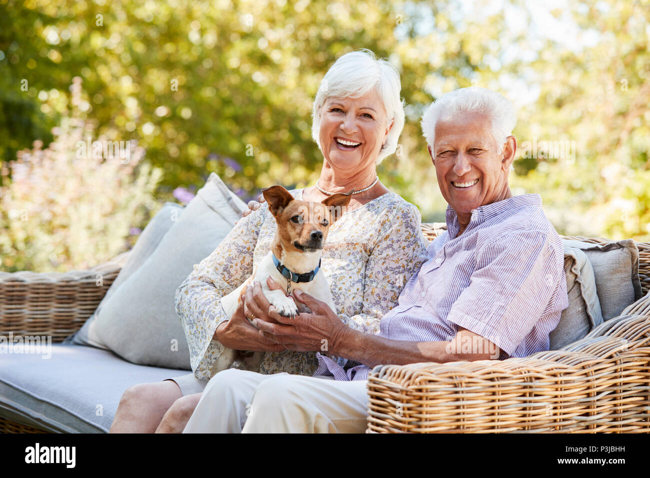 Gerne älteres Paar mit einem Haustier Hund im Garten Stockfoto