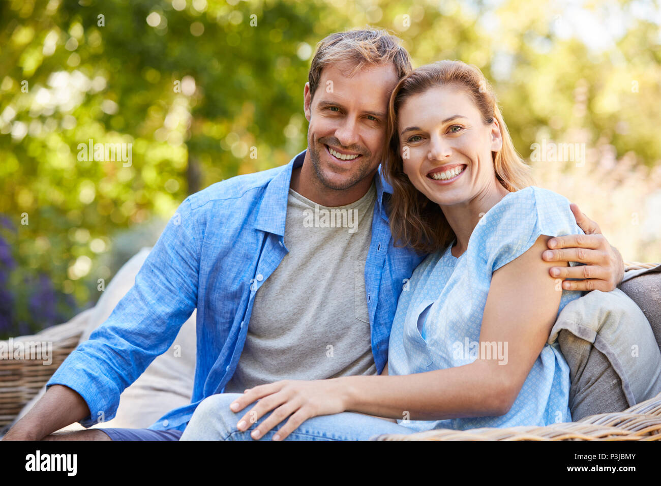 Glückliche junge weiß Paar sitzen und in den Garten Stockfoto