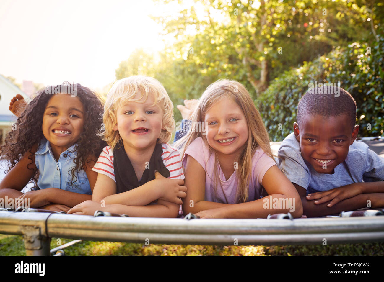 Vier Kinder zusammen liegen auf einem Trampolin im Garten Stockfoto